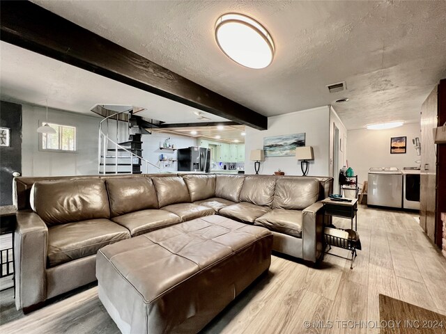 living room featuring light hardwood / wood-style flooring, a textured ceiling, beamed ceiling, and washing machine and clothes dryer