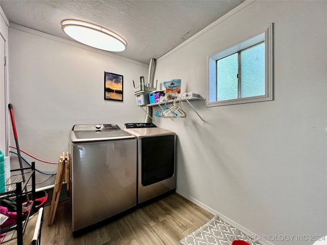 clothes washing area featuring light wood-type flooring, a textured ceiling, and washing machine and dryer