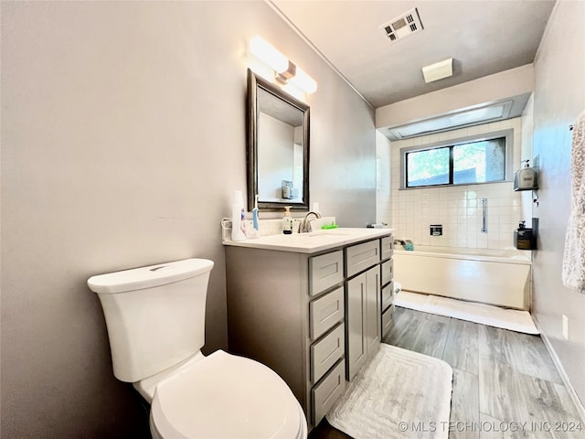 full bathroom with tiled shower / bath, hardwood / wood-style flooring, vanity, and toilet