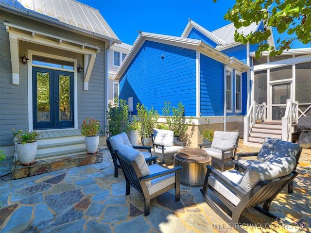 view of patio with a sunroom, an outdoor living space with a fire pit, and french doors