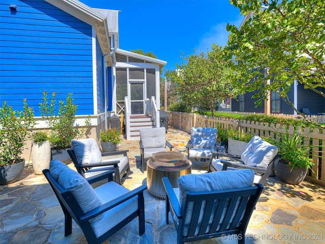 view of patio / terrace featuring a sunroom and an outdoor living space with a fire pit