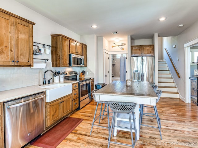 kitchen featuring a kitchen island, a breakfast bar, sink, decorative backsplash, and stainless steel appliances