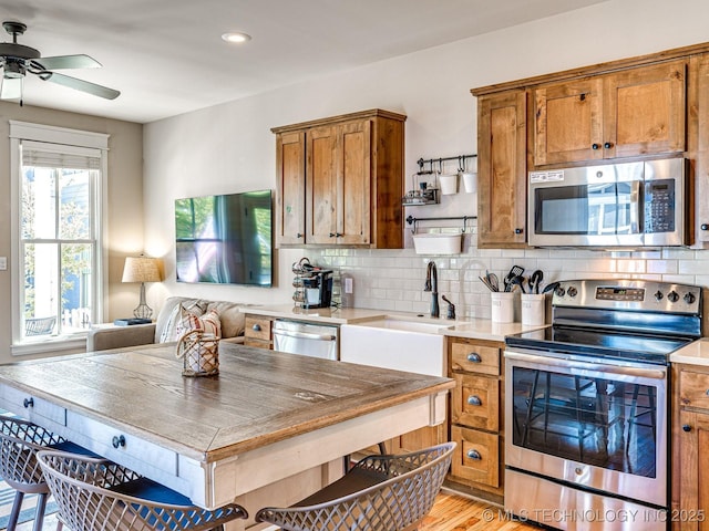 kitchen with sink, ceiling fan, stainless steel appliances, light hardwood / wood-style floors, and decorative backsplash