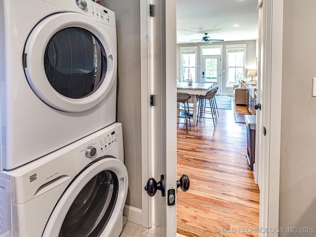 clothes washing area with stacked washer and dryer, ceiling fan, and light wood-type flooring