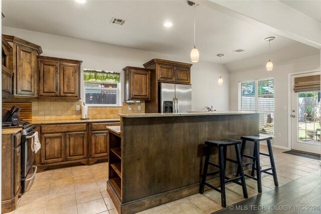 kitchen with a kitchen island, decorative backsplash, a kitchen bar, pendant lighting, and appliances with stainless steel finishes