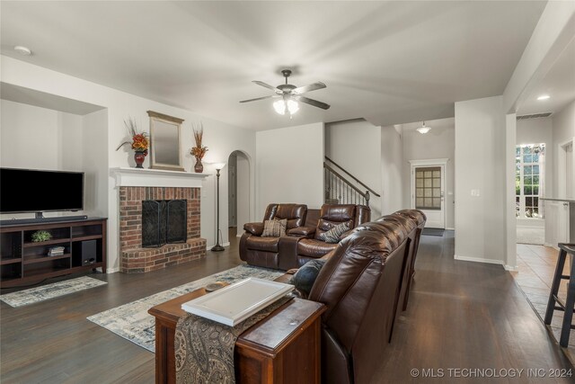 living room featuring ceiling fan, a brick fireplace, and dark hardwood / wood-style flooring