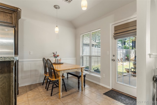 tiled dining room with a healthy amount of sunlight and vaulted ceiling