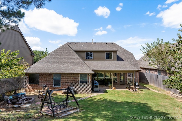 rear view of house with a patio, a fire pit, and a yard