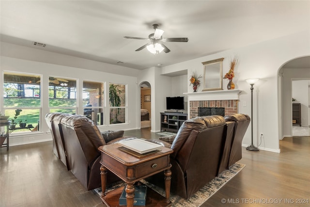 living room featuring ceiling fan, wood-type flooring, and a brick fireplace