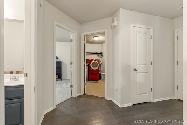 hallway with independent washer and dryer, sink, and dark hardwood / wood-style flooring