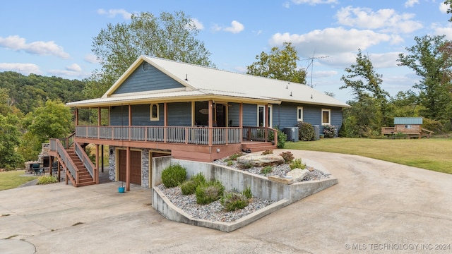 view of front facade featuring a front lawn, central AC, covered porch, and a garage