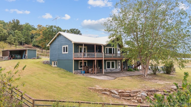 back of property featuring a yard, a patio, and an outbuilding