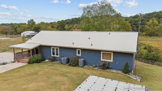 rear view of property featuring central AC unit, a yard, and covered porch