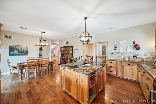 kitchen with hardwood / wood-style flooring, hanging light fixtures, sink, and tasteful backsplash