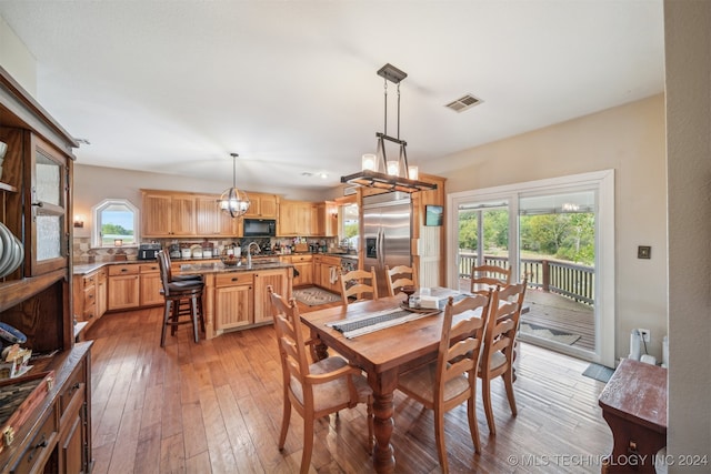 dining area with light wood-type flooring, an inviting chandelier, and sink