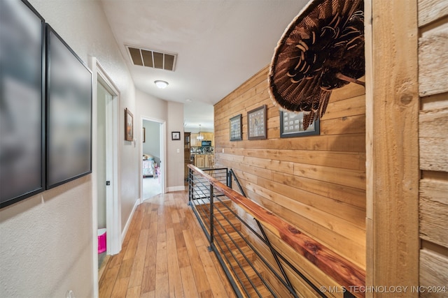 corridor featuring wooden walls and light wood-type flooring