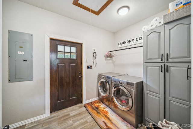 clothes washing area featuring independent washer and dryer, electric panel, light hardwood / wood-style flooring, and cabinets