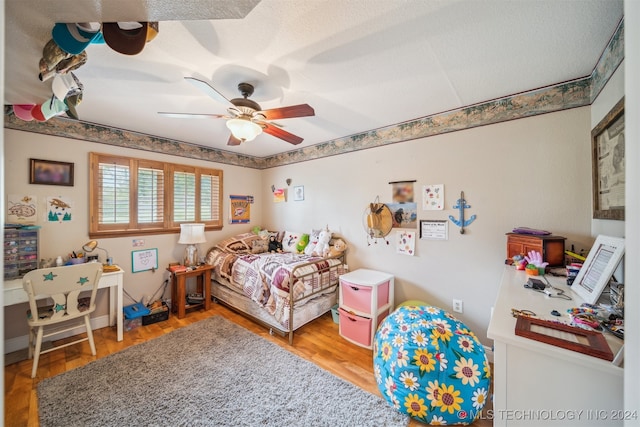 bedroom with ceiling fan, hardwood / wood-style floors, and a textured ceiling