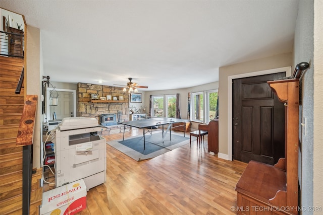 kitchen featuring ceiling fan, a stone fireplace, and light hardwood / wood-style flooring