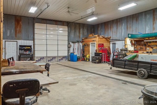 garage with a workshop area, ceiling fan, and wooden walls