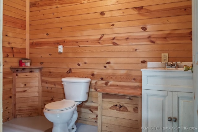 bathroom with wood walls, vanity, and toilet