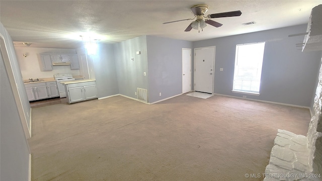 unfurnished living room featuring ceiling fan, light carpet, and sink