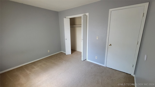 unfurnished bedroom featuring a closet and light colored carpet