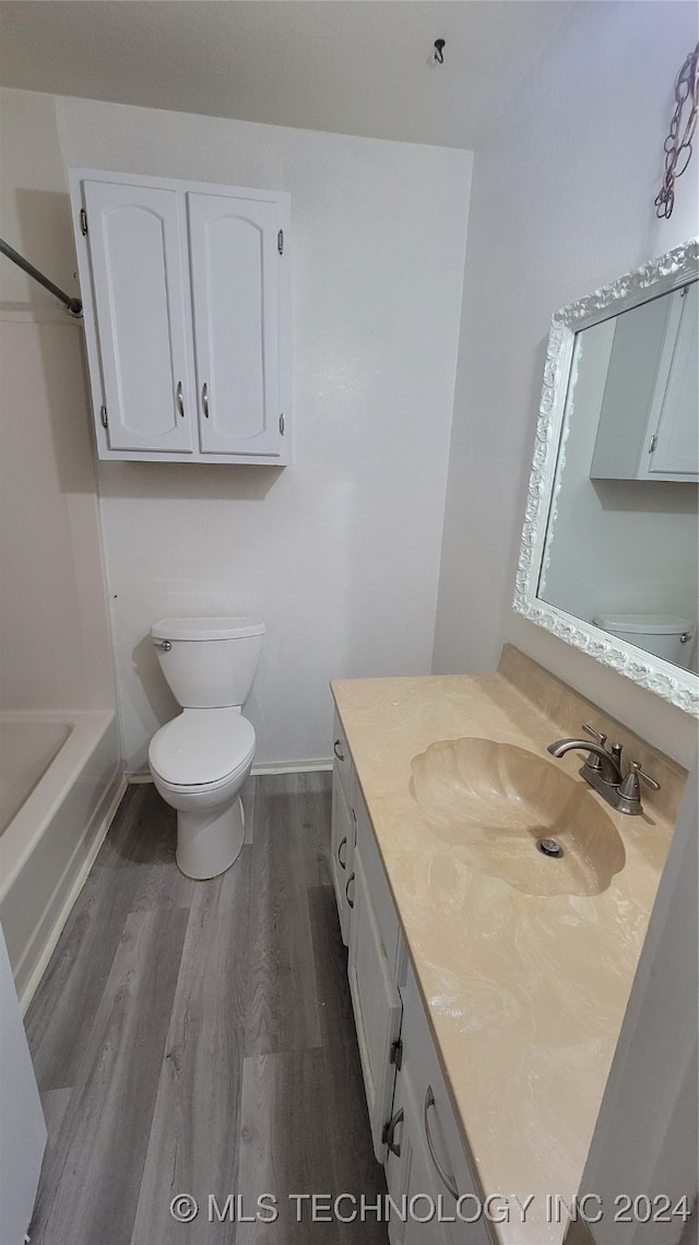 full bathroom with shower / washtub combination, vanity, toilet, and hardwood / wood-style flooring