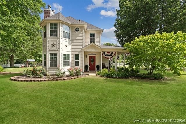 victorian home with a chimney and a front yard