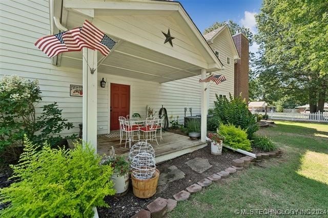 exterior space with a lawn, a chimney, outdoor dining area, and fence