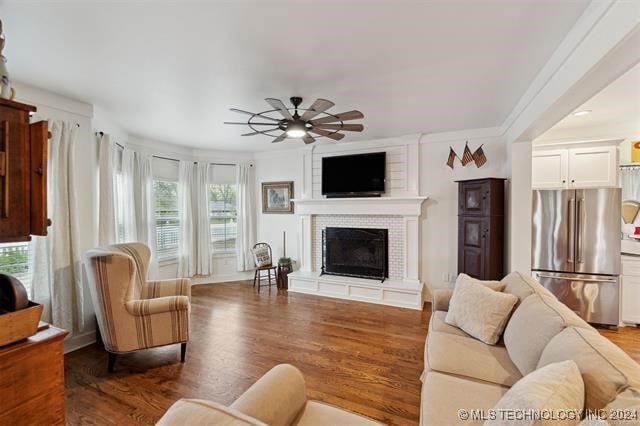 living room with ceiling fan, ornamental molding, a fireplace, and hardwood / wood-style floors