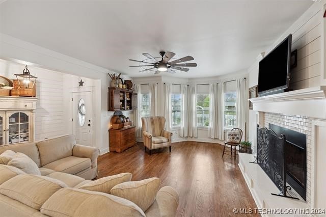 living room with ceiling fan, a fireplace, crown molding, and wood-type flooring