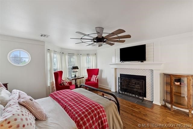 bedroom featuring a fireplace, dark hardwood / wood-style floors, and ceiling fan