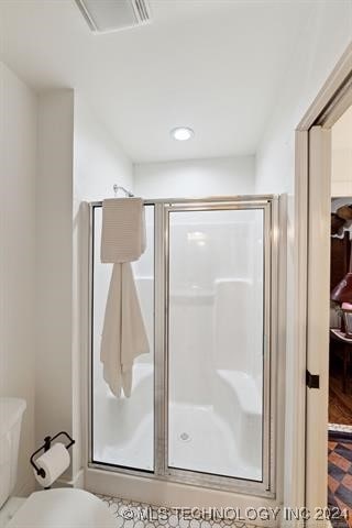full bath featuring visible vents, a shower stall, and toilet