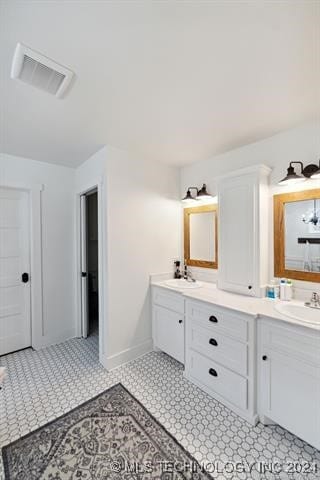 full bathroom with double vanity, baseboards, visible vents, and a sink