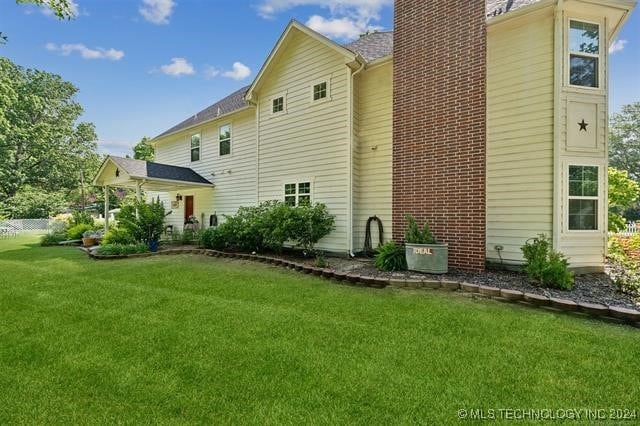 back of property with a chimney and a yard