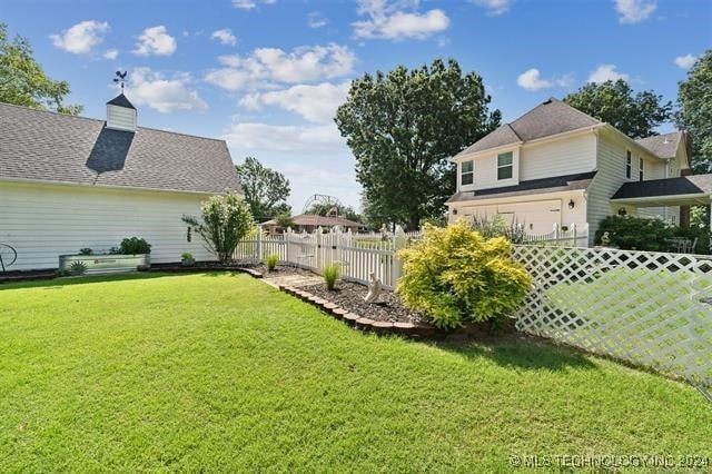 view of yard featuring an attached garage and fence