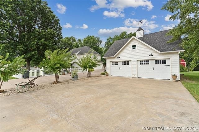 garage with concrete driveway and fence