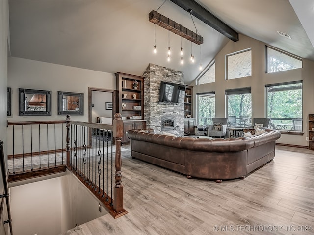 living room featuring a stone fireplace, light hardwood / wood-style flooring, beamed ceiling, and high vaulted ceiling