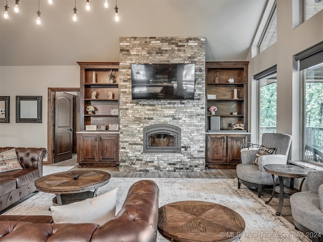 living room featuring a fireplace, built in features, high vaulted ceiling, and light hardwood / wood-style flooring