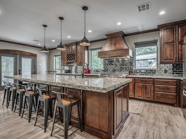 kitchen featuring plenty of natural light, a spacious island, and custom exhaust hood