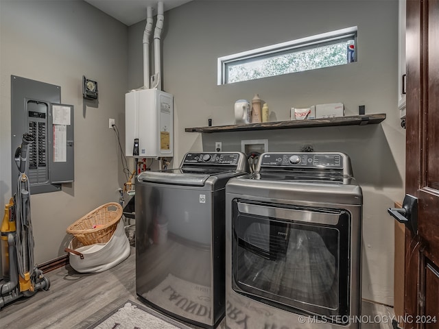 clothes washing area with hardwood / wood-style floors, washing machine and dryer, tankless water heater, and electric panel