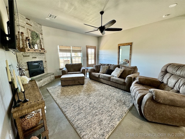 living room with a textured ceiling, ceiling fan, a fireplace, and concrete floors