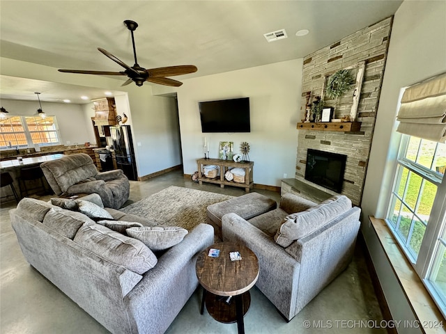 living room with concrete flooring, ceiling fan, and a healthy amount of sunlight