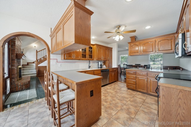 kitchen with ceiling fan, stainless steel appliances, backsplash, kitchen peninsula, and a breakfast bar