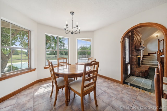 tiled dining room with a chandelier and a textured ceiling