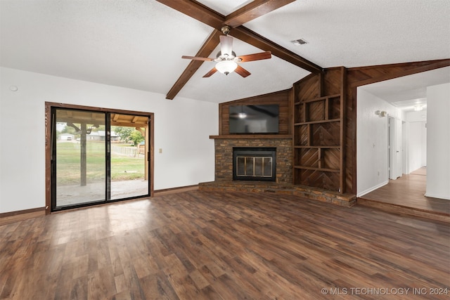 unfurnished living room featuring dark wood-type flooring, vaulted ceiling with beams, a textured ceiling, and a stone fireplace