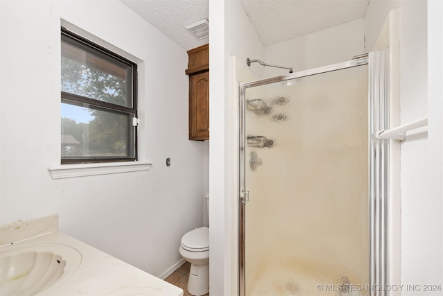 bathroom featuring toilet, tile patterned floors, a shower with door, vanity, and a textured ceiling