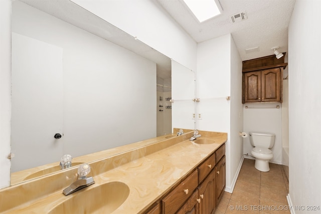 bathroom featuring vanity, toilet, a textured ceiling, and tile patterned floors