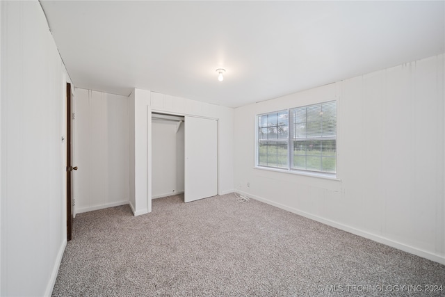 unfurnished bedroom with light carpet and a closet